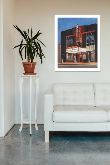 A modern living space featuring a potted plant, a white couch, and a framed artwork on the wall.