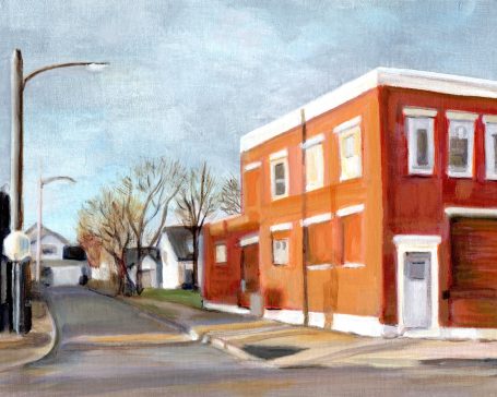 Red brick building in a quiet street with bare trees under a cloudy sky.