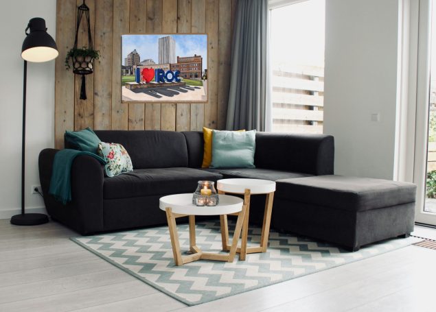 Modern living room with a black sectional sofa, decorative pillows, and a wall art piece.