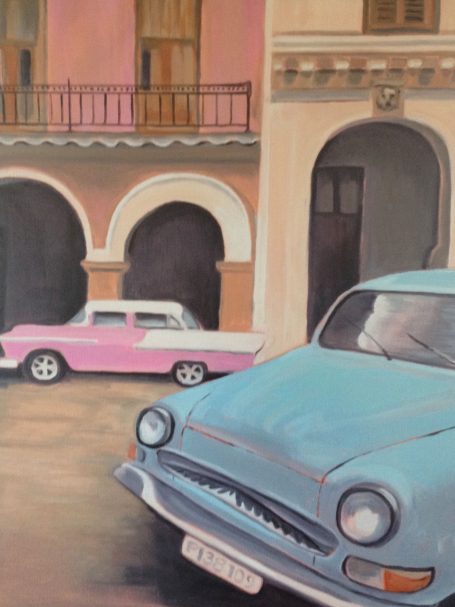 Vintage cars parked on a cobblestone street with colorful buildings in the background.